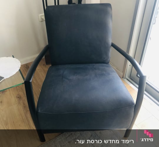 כורסה מרופדת בבד כהה עם ידיות מתכת